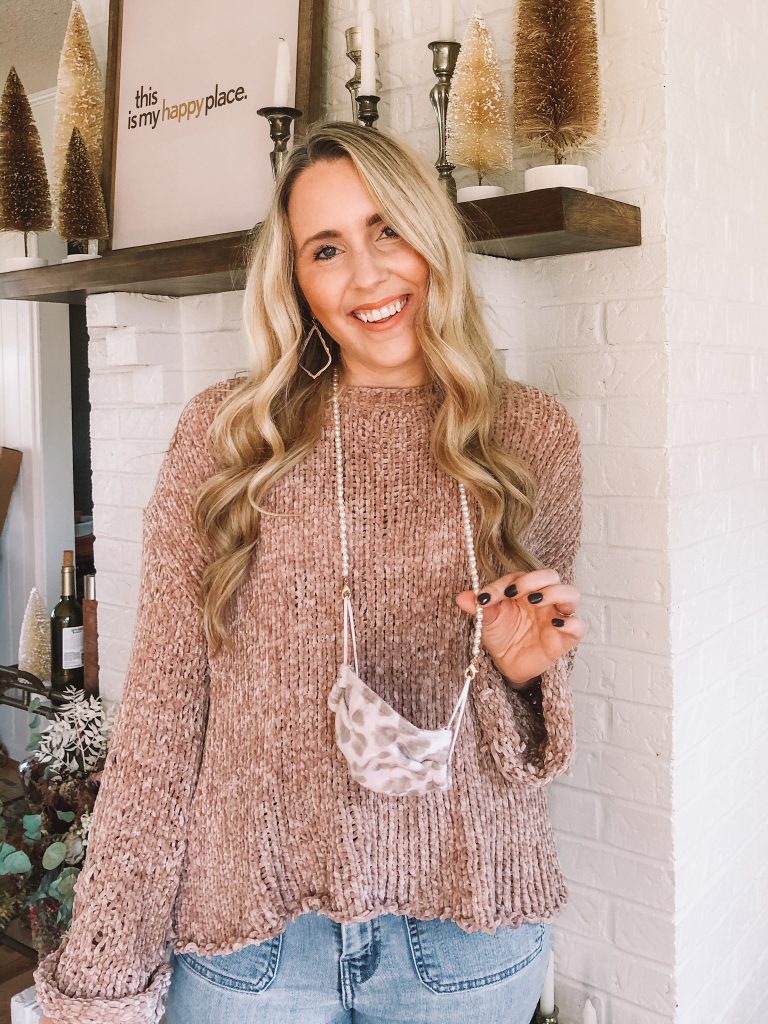 Mask Chains by popular Nashville life and style blog, Pearls and Twirls: image of a woman wearing a pearl face mask chain, jeans, leopard print mask and champagne colored sweater. 
